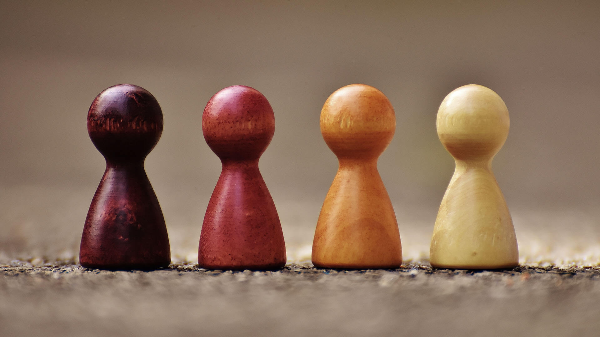 Four wooden pawns in a row, each of a different color