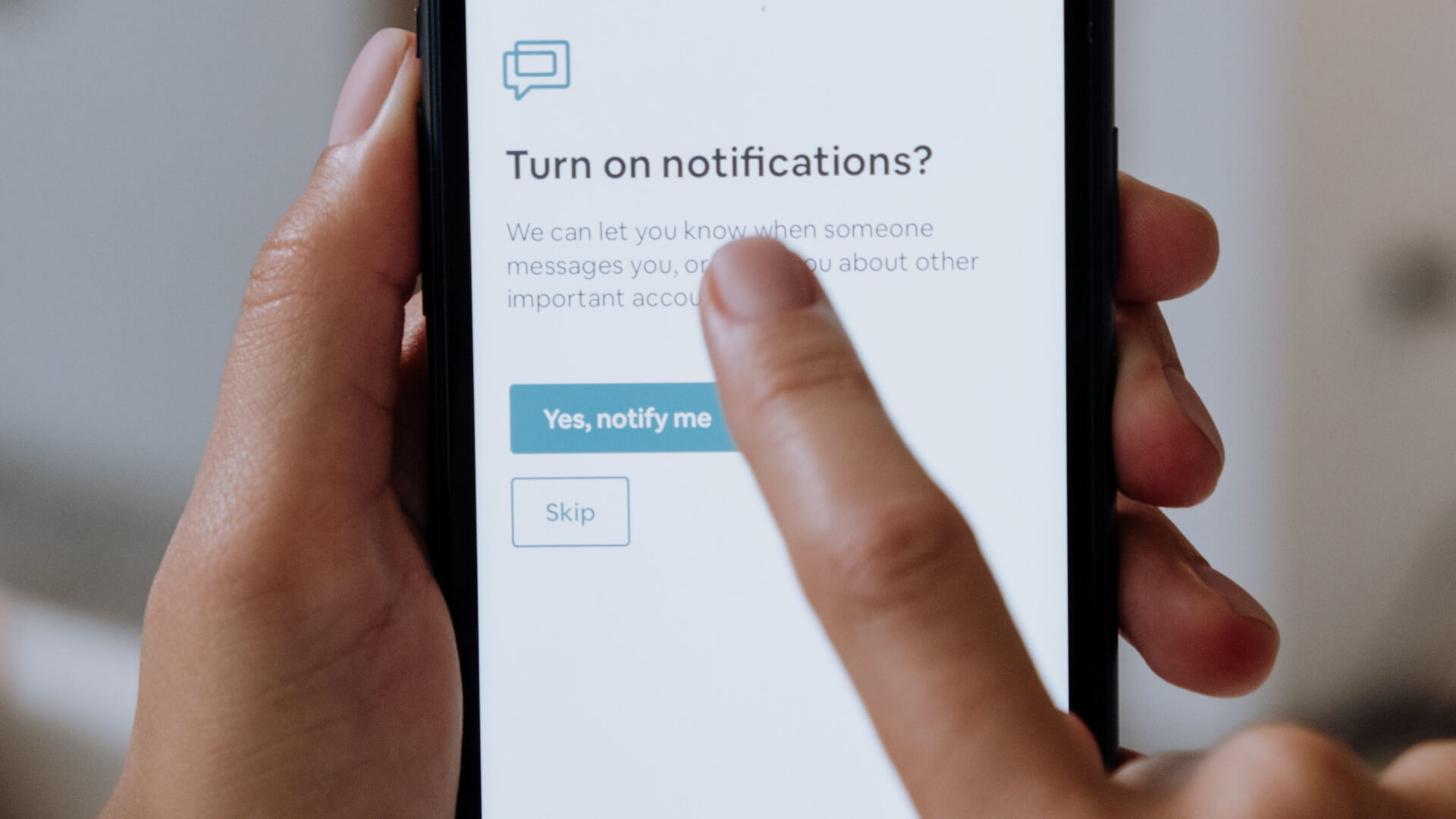 A finger about to tap "Yes, notify me" on a phone that asks to turn on notifications